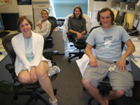 Group members (front-to-back, left-to-right: Amy Grimes, Mark Jackson, Julie Maylor, and Candace Pfefferkorn) sitting at desks in the lab office